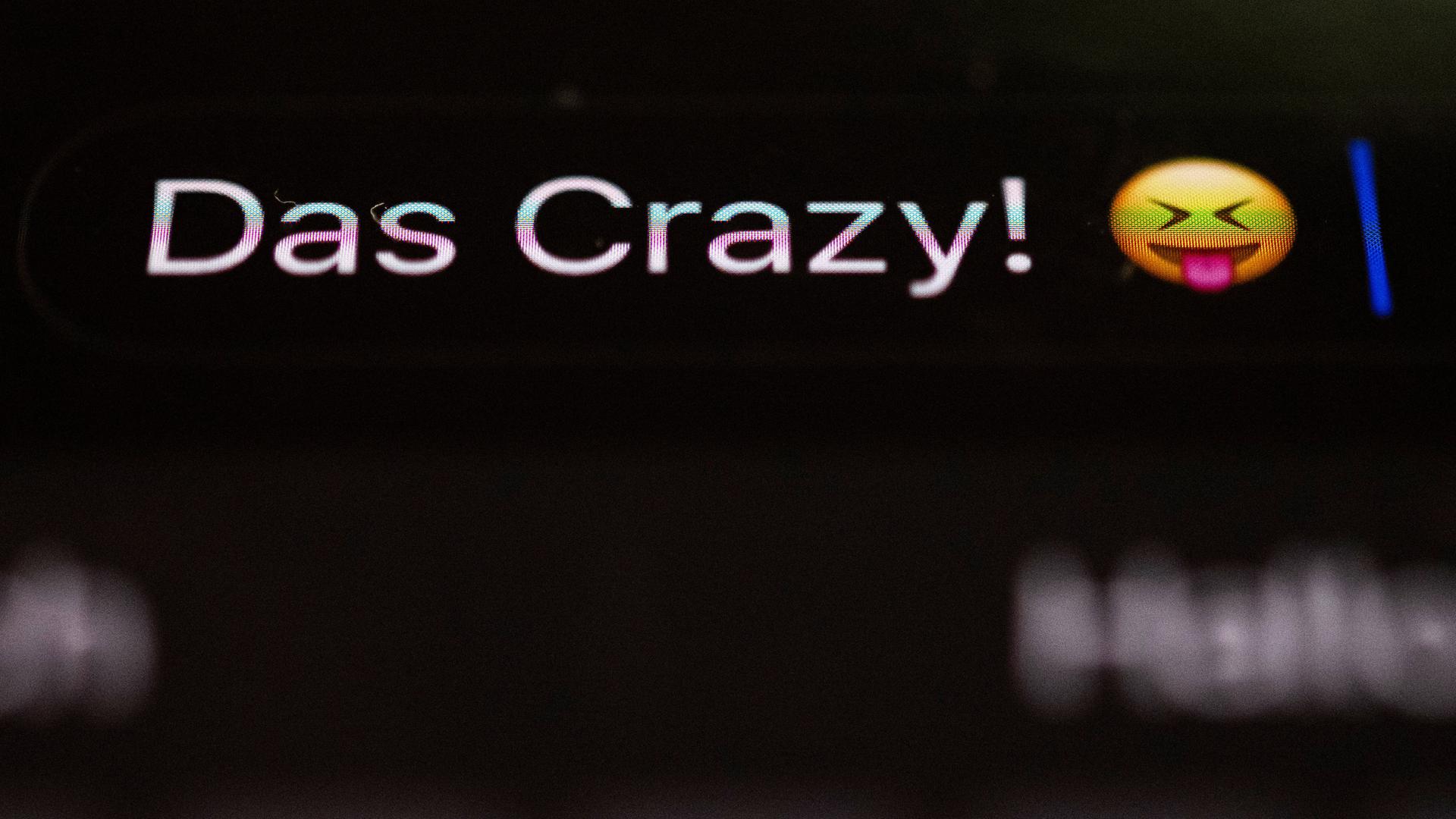 Die Worte "Das Crazy" sind auf dem Display eines Smartphones zu sehen. Die Worte "Das Crazy" sind auf dem Display eines Smartphones zu sehen.