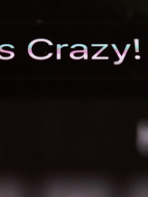 Die Worte "Das Crazy" sind auf dem Display eines Smartphones zu sehen.