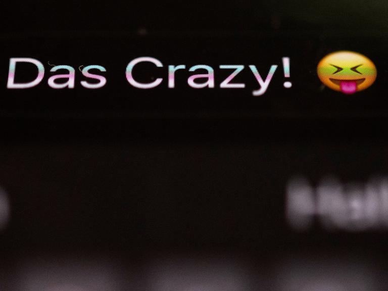 Die Worte "Das Crazy" sind auf dem Display eines Smartphones zu sehen.