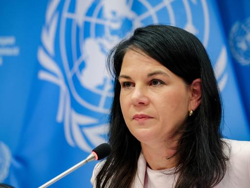 Annalena Baerbock, Präsidentin der 80. UN-Generalversammlung, sitzt vor einem Mikrofon. Im Hintergrund hängt die Flagge der Vereinten Nationen.