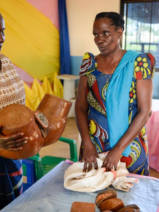 Zwei Frauen mit einem Model einer Vulva an dem die Grausamkeit der Genitalverstümmelung nachvollzogen werden kann.