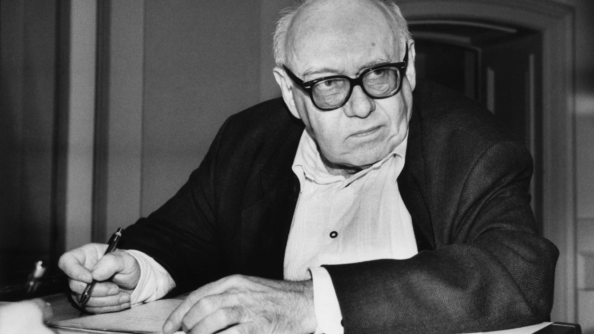 Das Foto zeigt den Dichter Ernst Jandl an einem Tisch sitzend mit Notizblock und Stift in der Hand. Das Foto zeigt den Dichter Ernst Jandl an einem Tisch sitzend mit Notizblock und Stift in der Hand.