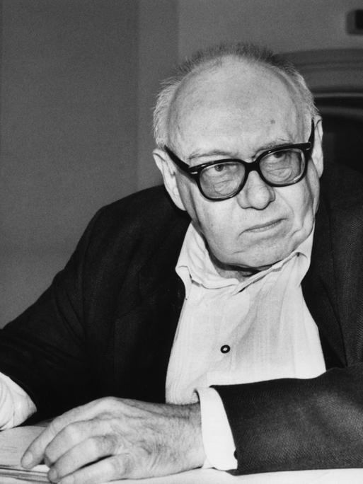 Das Foto zeigt den Dichter Ernst Jandl an einem Tisch sitzend mit Notizblock und Stift in der Hand.