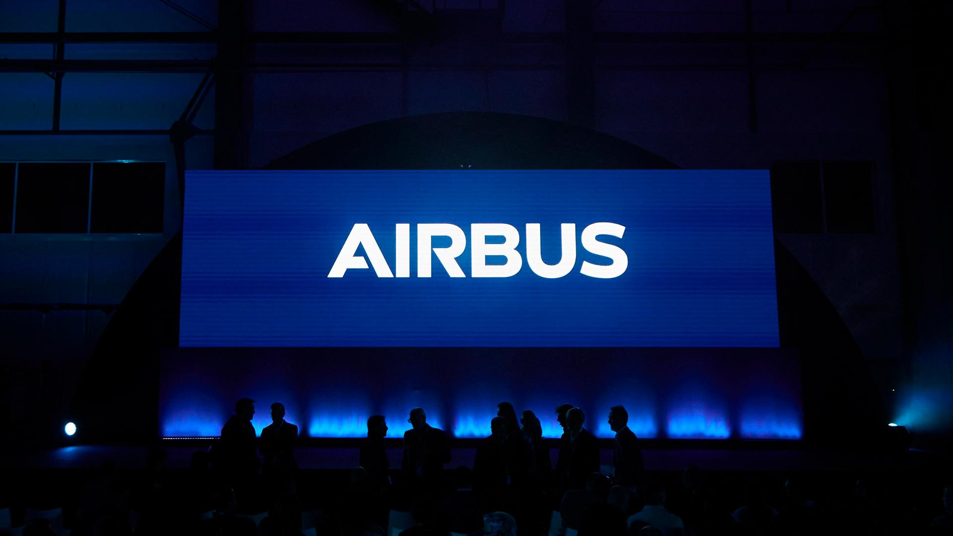 Das Airbus-Logo leuchtet vor dunklem Hintergrund. 
