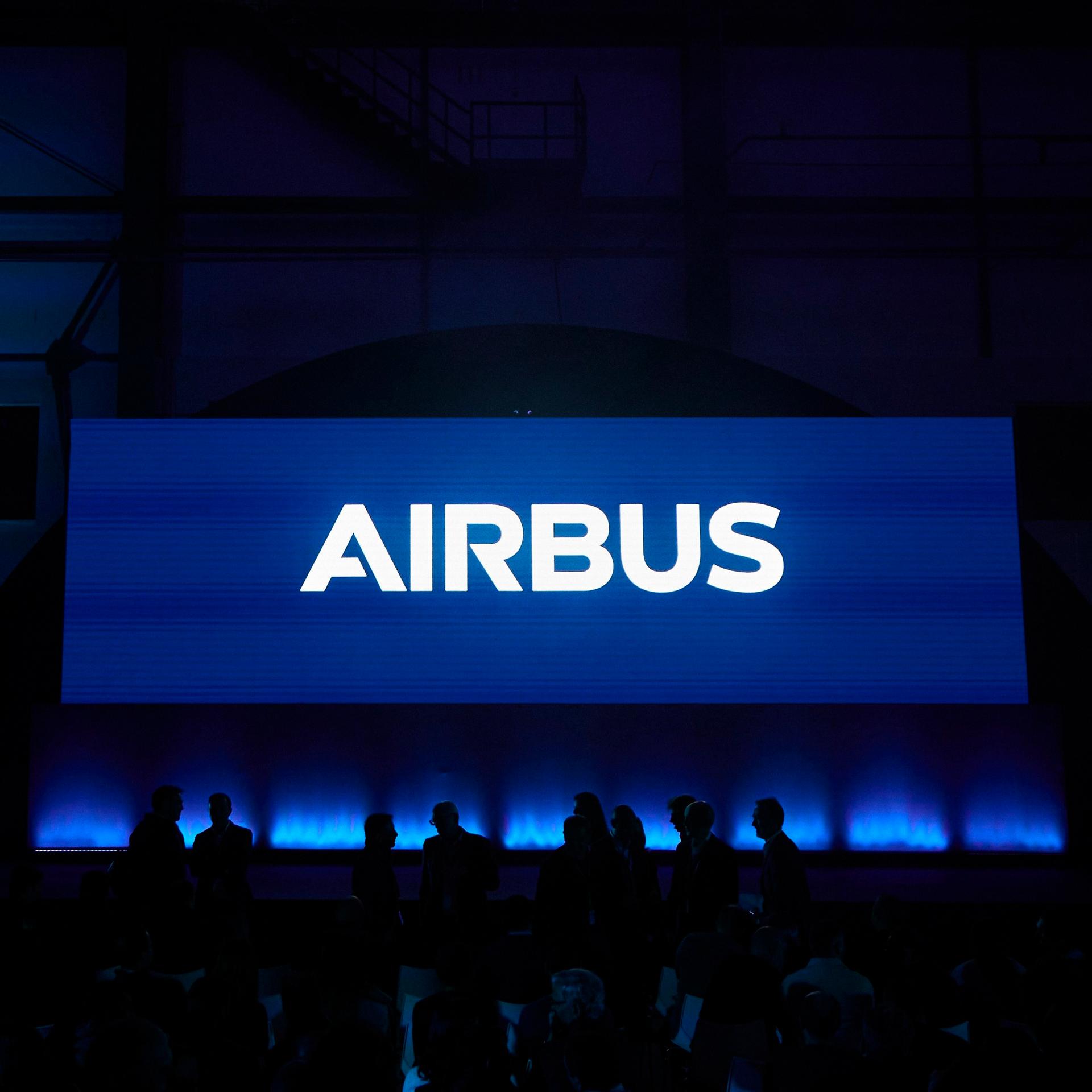 Das Airbus-Logo leuchtet vor dunklem Hintergrund. 