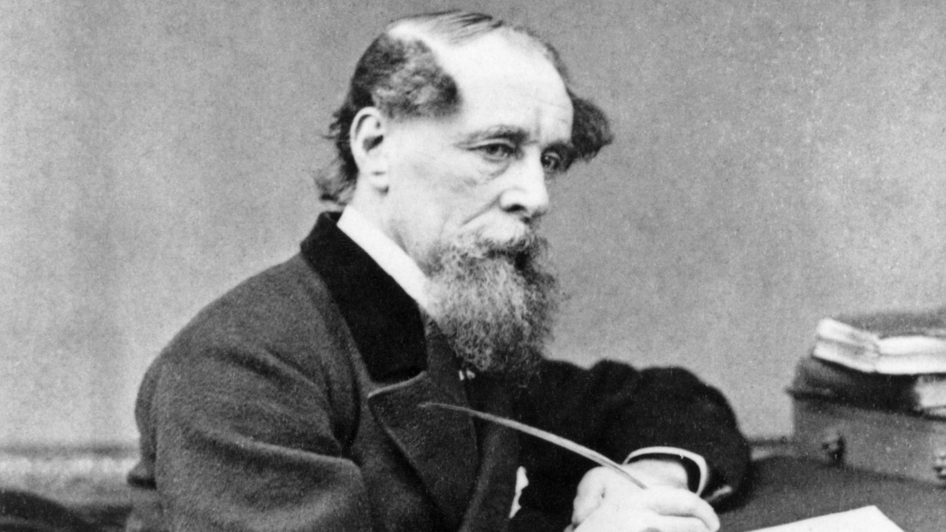 Schwarzweißporträt von Charles Dickens in nachdenklicher Pose am Schreibtisch