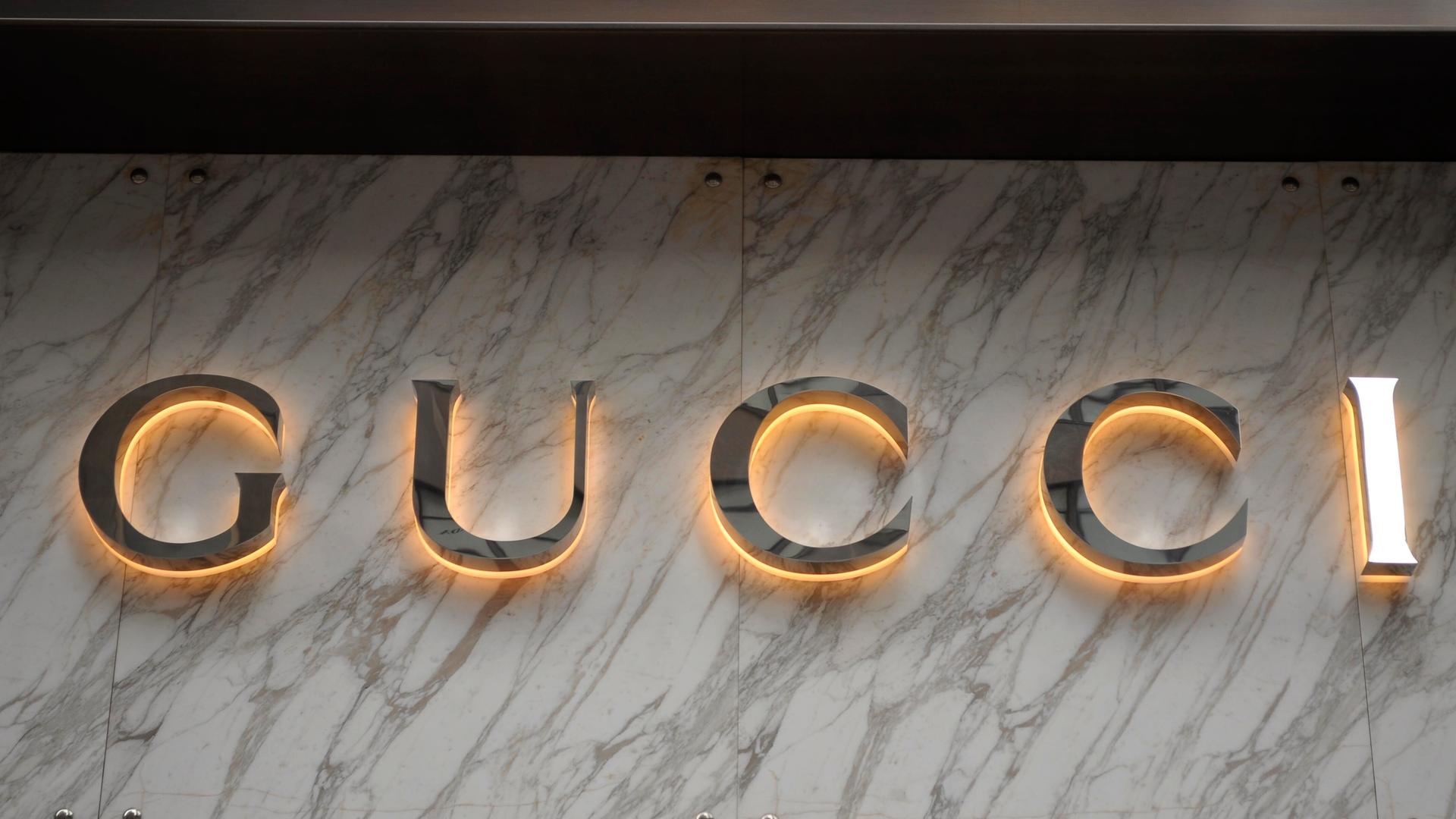 Die Gucci-Buchstaben in Gold auf einer Marmorplatte. Die Gucci-Buchstaben in Gold auf einer Marmorplatte.