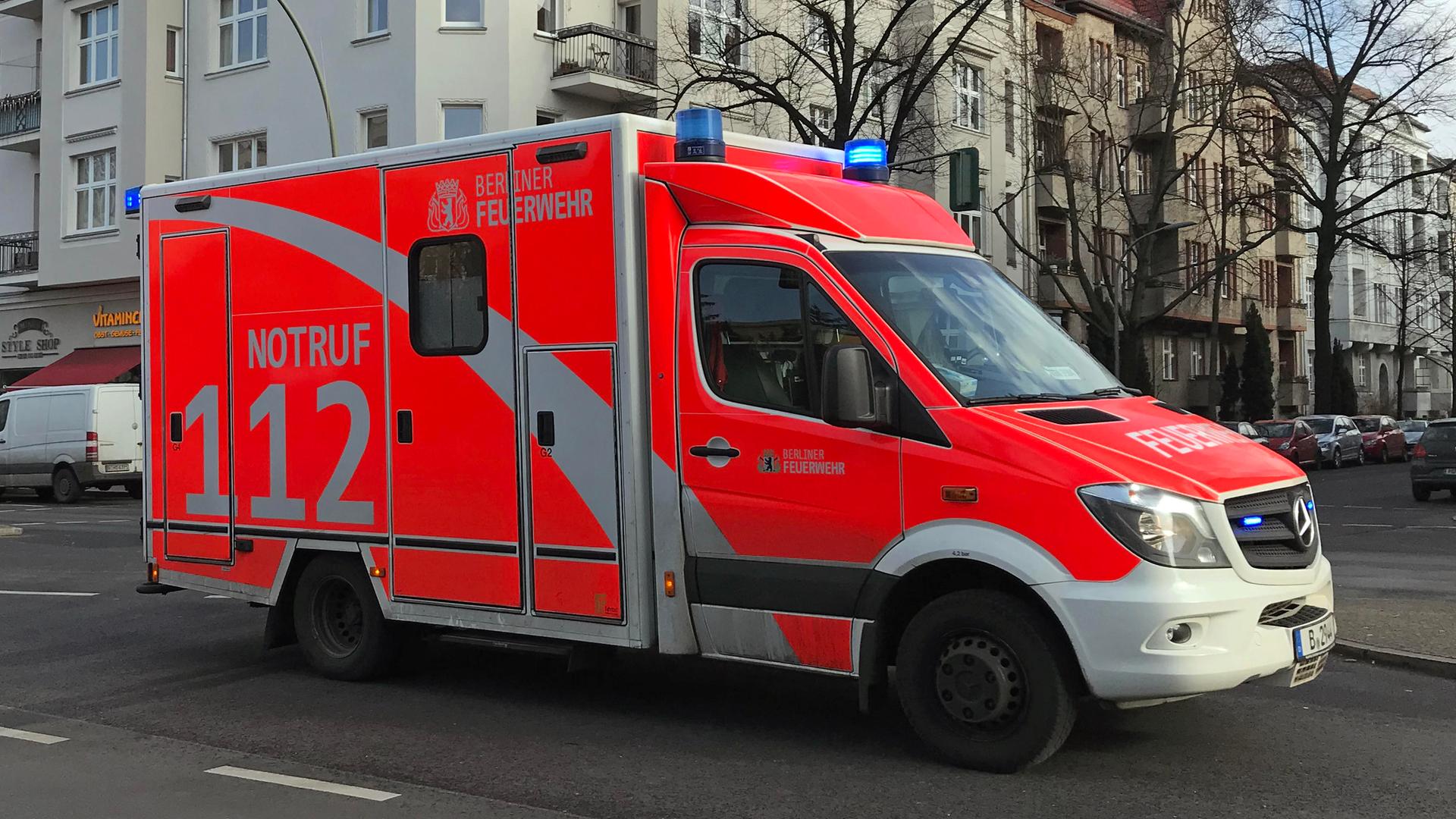 Ein Rettungswagen der Berliner Feuerwehr fährt über eine Straße. Im Hintergrund sind kahle Bäume und Häuser zu sehen. 