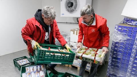 Freiwillige Helfer beladen im Kühlraum Kisten mit Nahrungsmitteln bei der Hamburger Tafel.