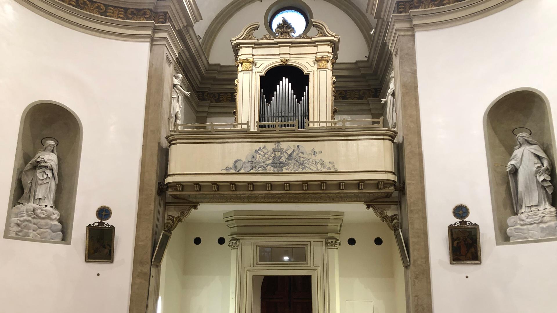 Eine Frau verlässt den Kirchenraum, um sich einer barocken Orgel auf der Empore zu begeben.