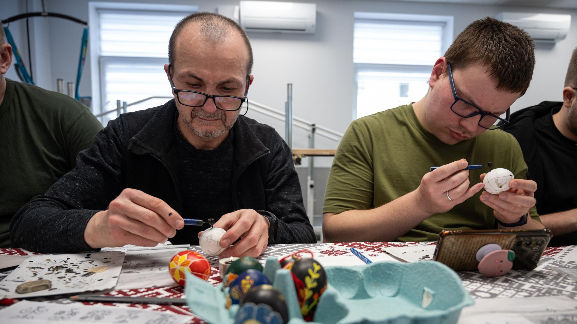 Zwei Männer, die Ostereier anmalen 