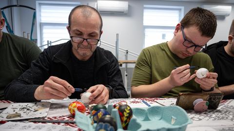 Zwei Männer, die Ostereier anmalen 