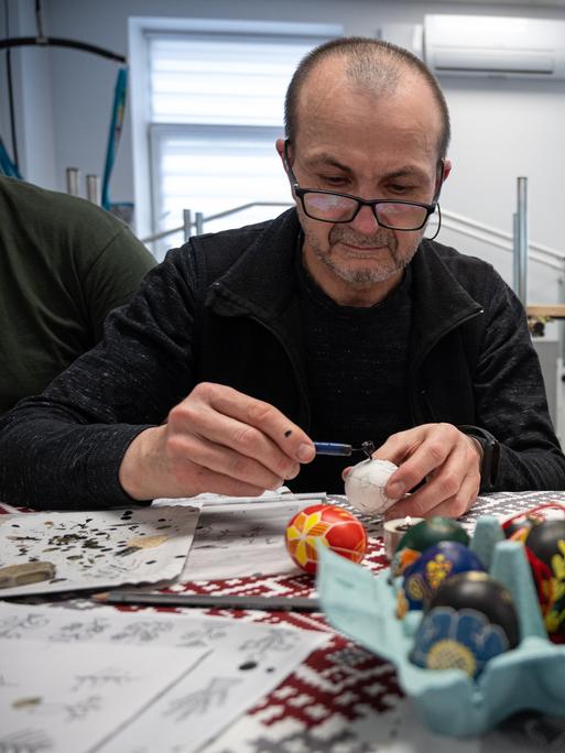 Zwei Männer, die Ostereier anmalen 