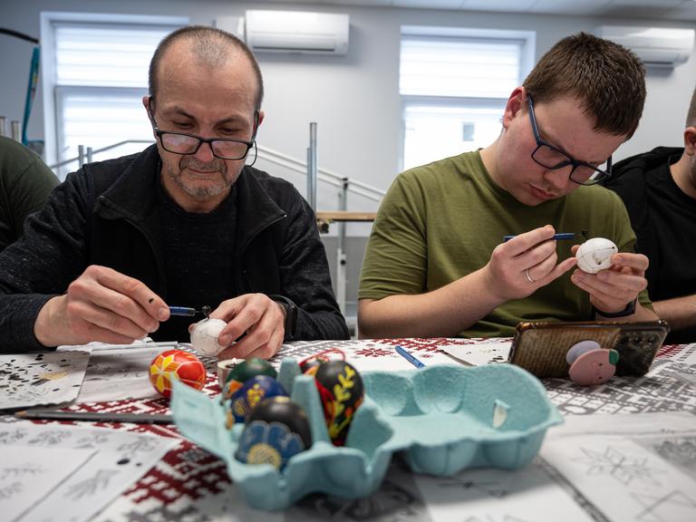 Zwei Männer, die Ostereier anmalen 