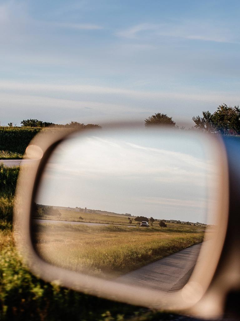 Der Seitenspiegel eines Autos, man sieht eine Landschaft.