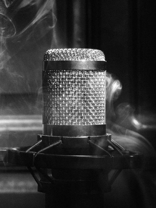 Schwarz-Weiß-Close-Up eines Mikrofons umgeben von Rauch.
