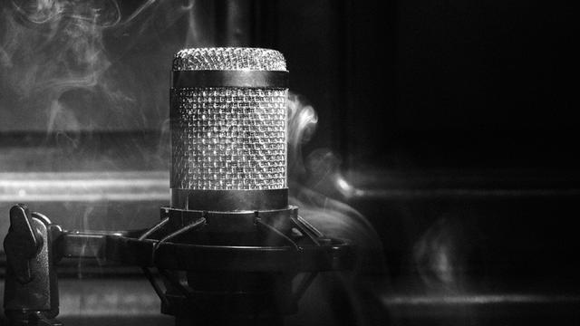 Schwarz-Weiß-Close-Up eines Mikrofons umgeben von Rauch.