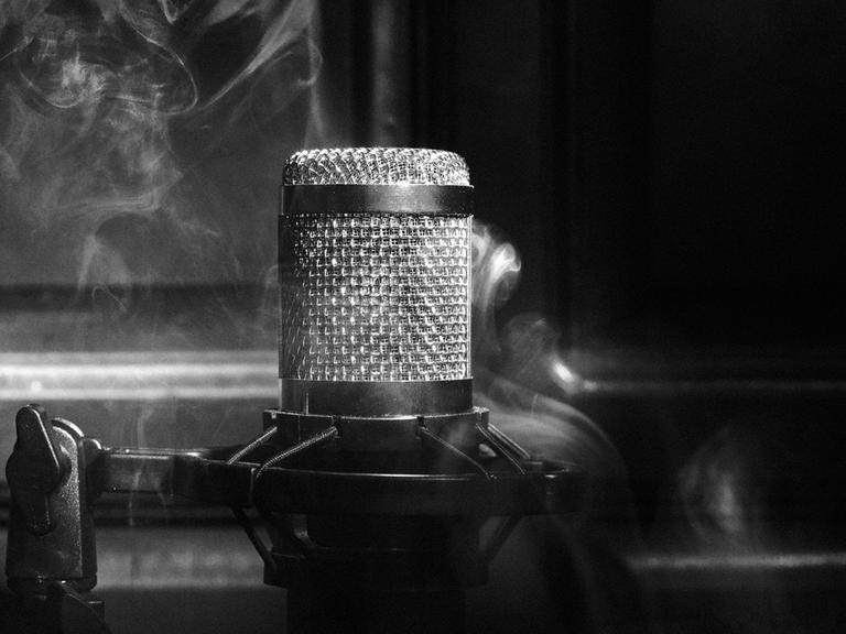 Schwarz-Weiß-Close-Up eines Mikrofons umgeben von Rauch.