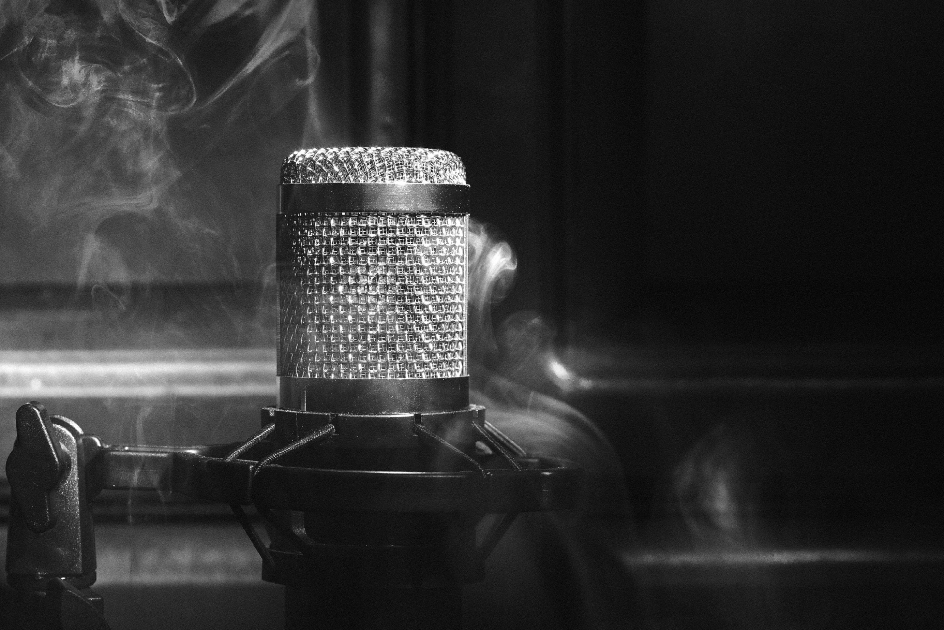Schwarz-Weiß-Close-Up eines Mikrofons umgeben von Rauch.