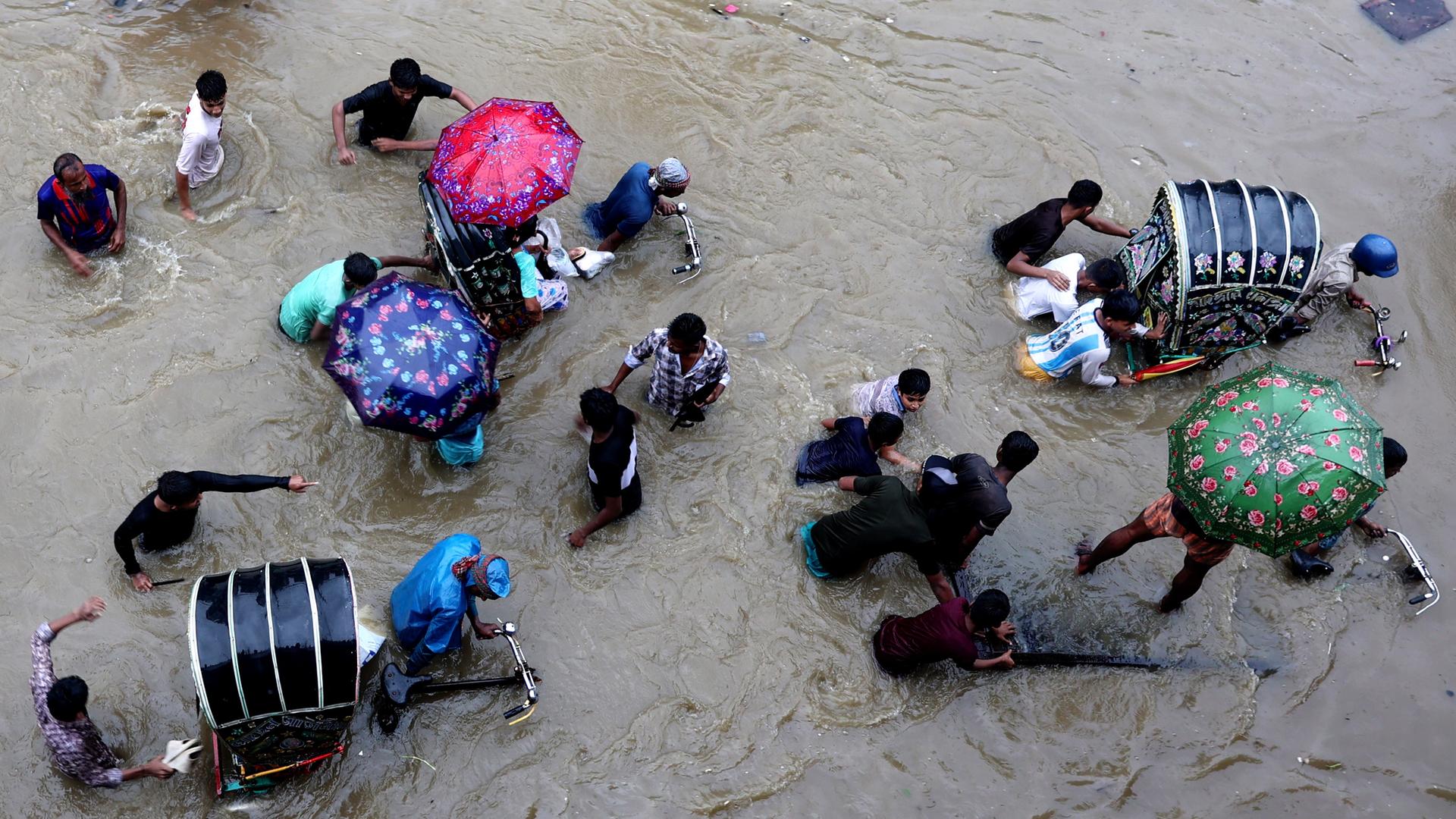 Bangladesch, Chittagong: Menschen waten durch eine überschwemmte Straße. Bangladesch, Chittagong: Menschen waten durch eine überschwemmte Straße.