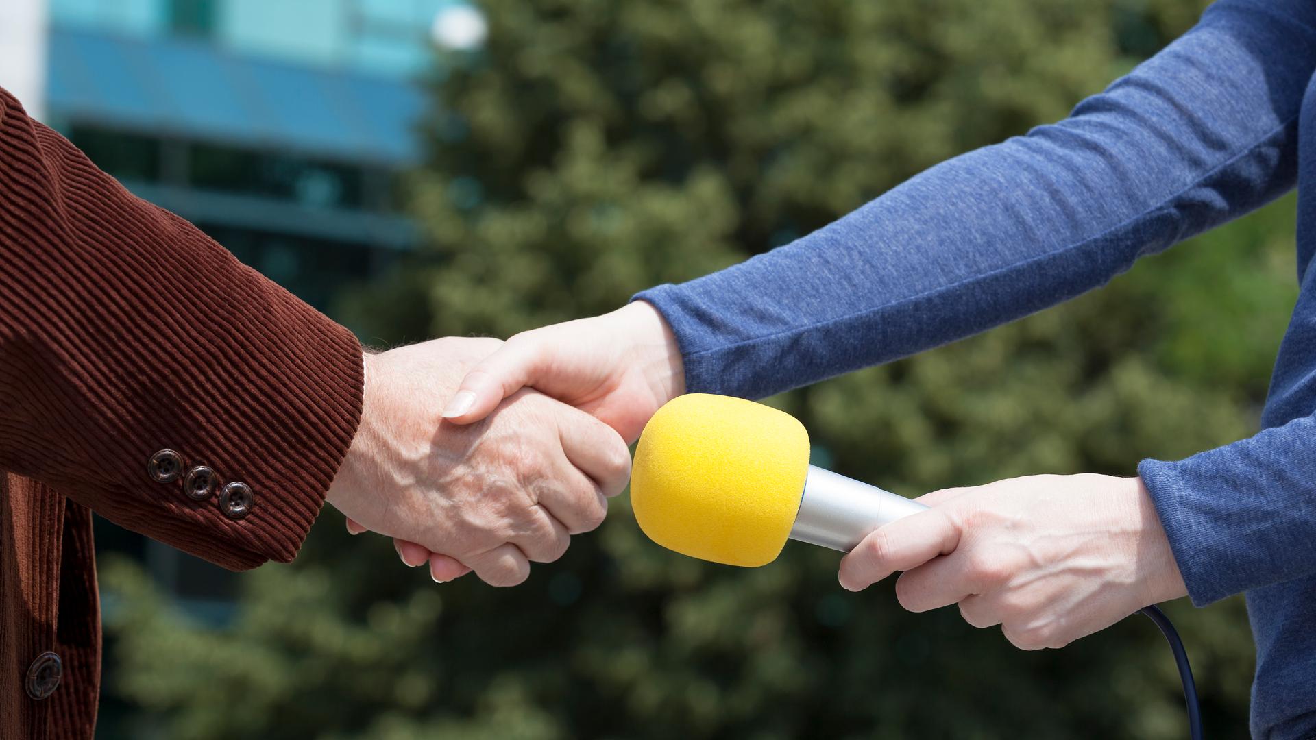Handschlag zwischen Reporterin und Interviewpartner vor einem Interview