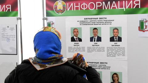 Eine Frau liest bei der vorzeitigen Stimmabgabe in einem Wahllokal in Minsk Informationen zu Kandidatinnen und Kandidaten.