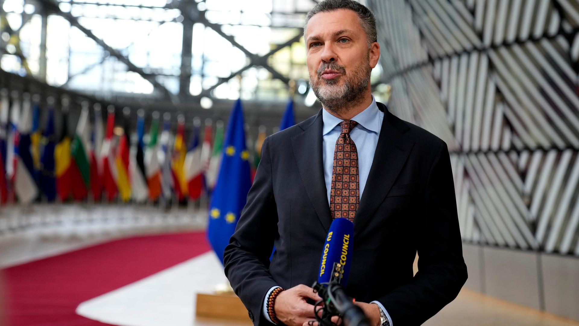 Visentini steht vor einem Mikrofon. Im Hintergrund sind Flaggen der EU zu sehen. Visentini steht vor einem Mikrofon. Im Hintergrund sind Flaggen der EU zu sehen.