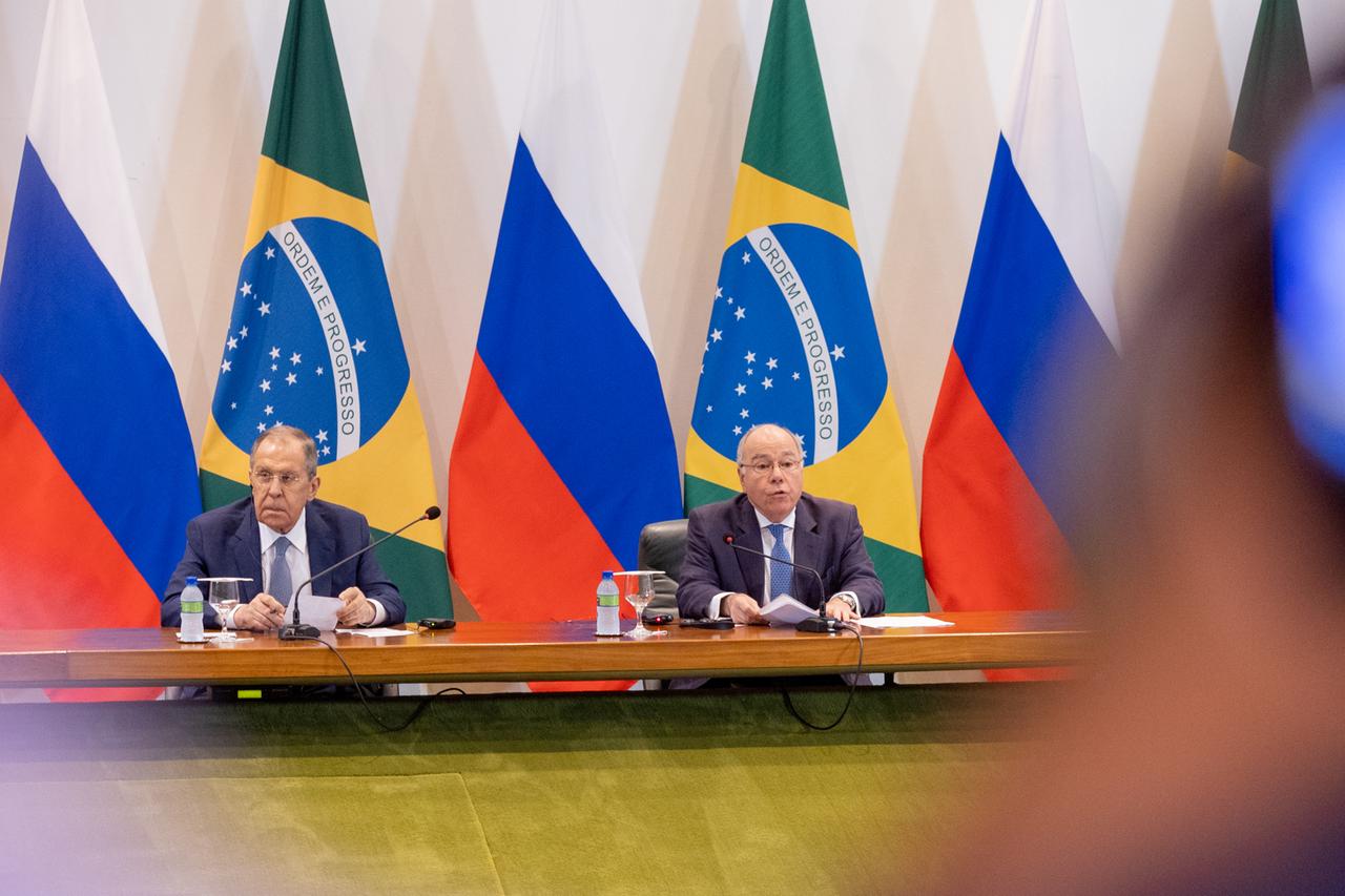 Der russische Außenminister und sein brasilianischer Kollege sitzen an einem Konferenztisch. Im Hintergrund sind mehrere Flaggen von Russland sowie von Brasilien zu sehen. 