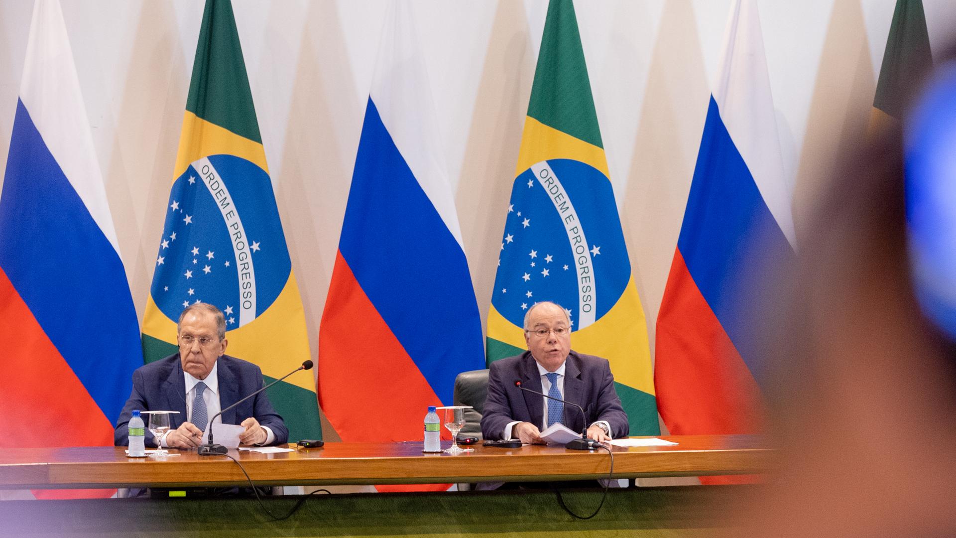 Der russische Außenminister und sein brasilianischer Kollege sitzen an einem Konferenztisch. Im Hintergrund sind mehrere Flaggen von Russland sowie von Brasilien zu sehen.