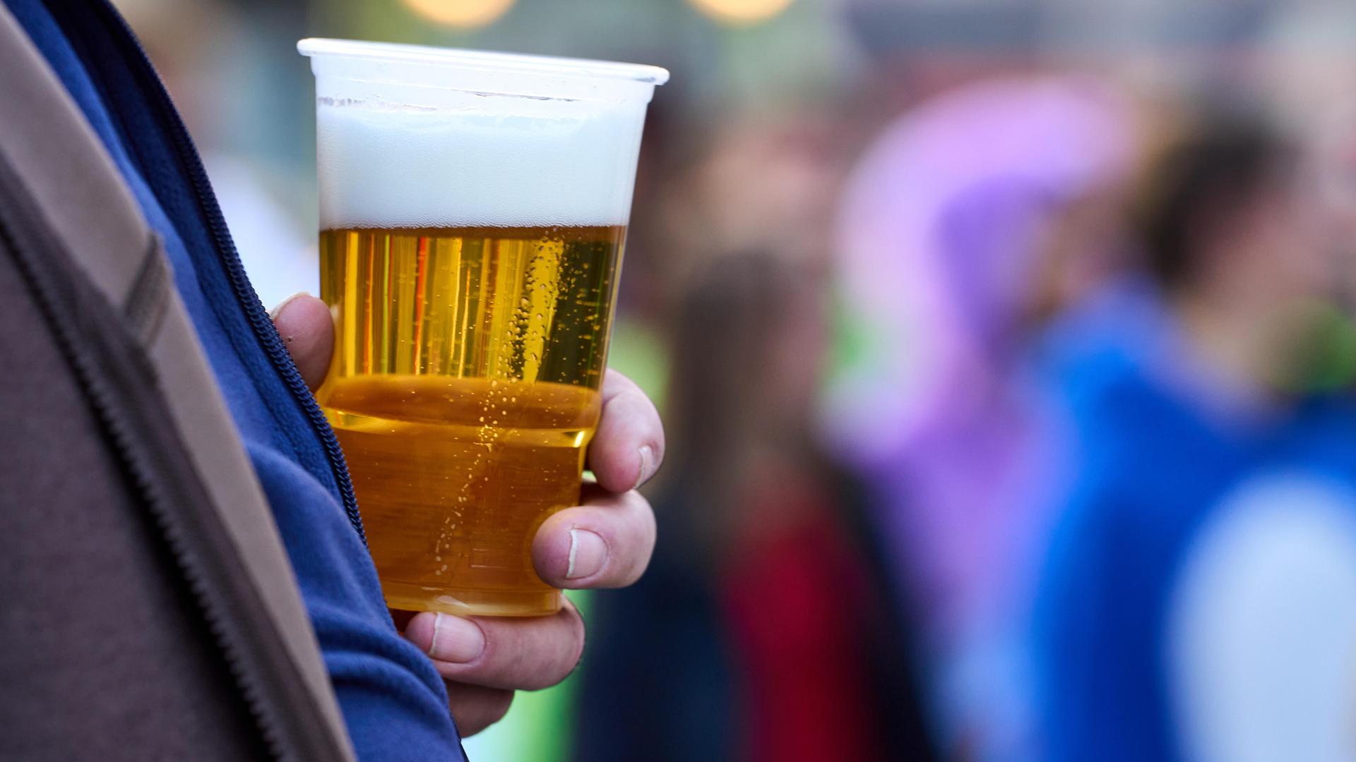 Ein Mann hält einen Becher mit Bier 