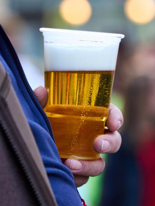 Ein Mann hält einen Becher mit Bier 