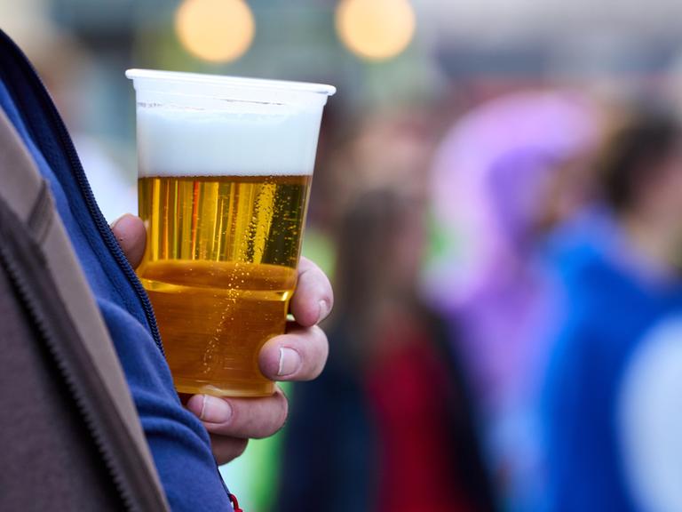 Ein Mann hält einen Becher mit Bier 