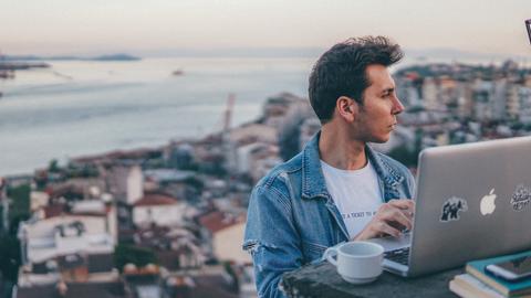 Ein junger Mann sitzt in Istanbul im Freien vor seinem Laptop.