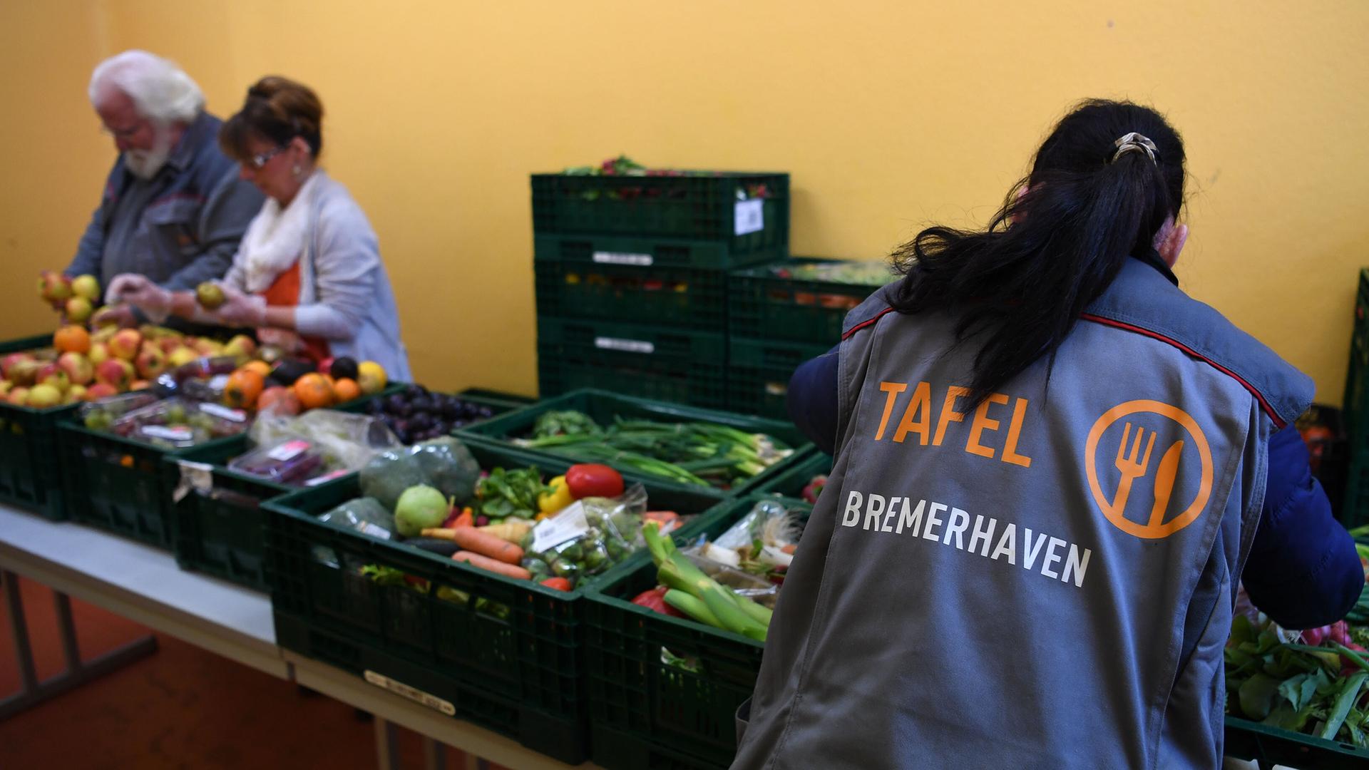 Eine Mitarbeiterin der Bremerhavener Tafel bereitet Obst und Gemüse zur Verteilung vor. Im Hintergrund sind zwei weitere Mitarbeitende zu sehen.