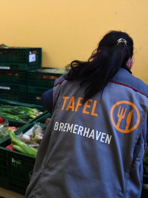Eine Mitarbeiterin der Bremerhavener Tafel bereitet Obst und Gemüse zur Verteilung vor. Im Hintergrund sind zwei weitere Mitarbeitende zu sehen. Eine Mitarbeiterin der Bremerhavener Tafel bereitet Obst und Gemüse zur Verteilung vor. Im Hintergrund sind zwei weitere Mitarbeitende zu sehen.