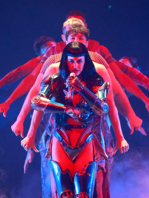 Katy Perry in einer Art Rüstung bei einem Konzert im August 2025, dahinter performen Tänzer