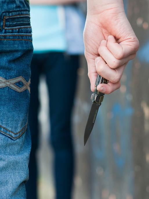 Ein Junge bedroht ein Mädchen mit einem Messe.