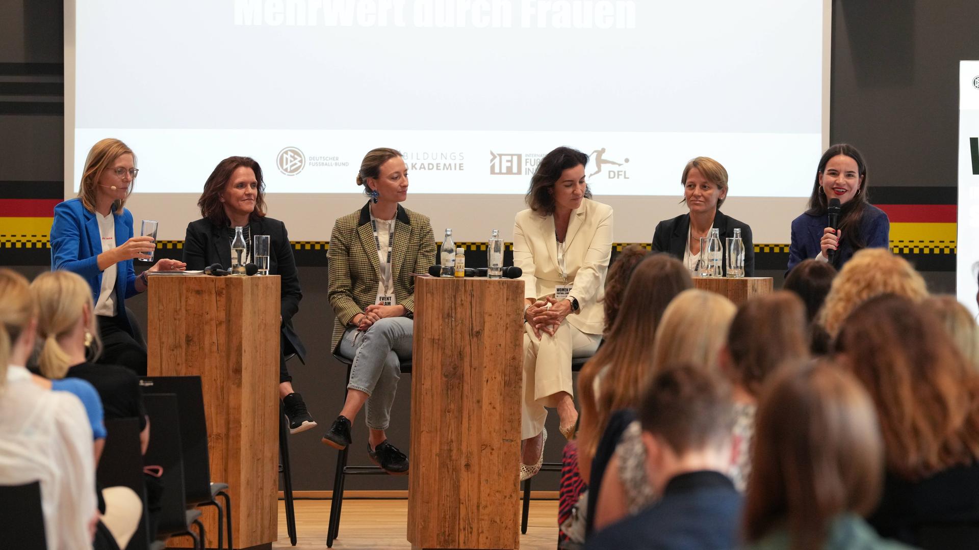 Beim Kongress sitzen sechs Frauen auf der Bühne und sprechen miteinander.