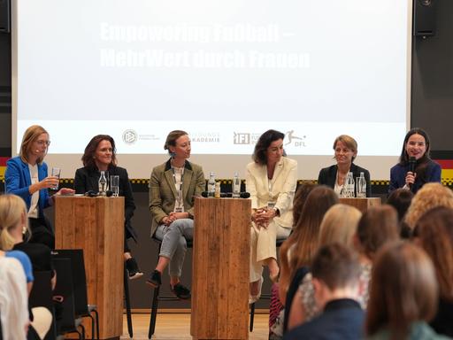 Beim Kongress sitzen sechs Frauen auf der Bühne und sprechen miteinander.