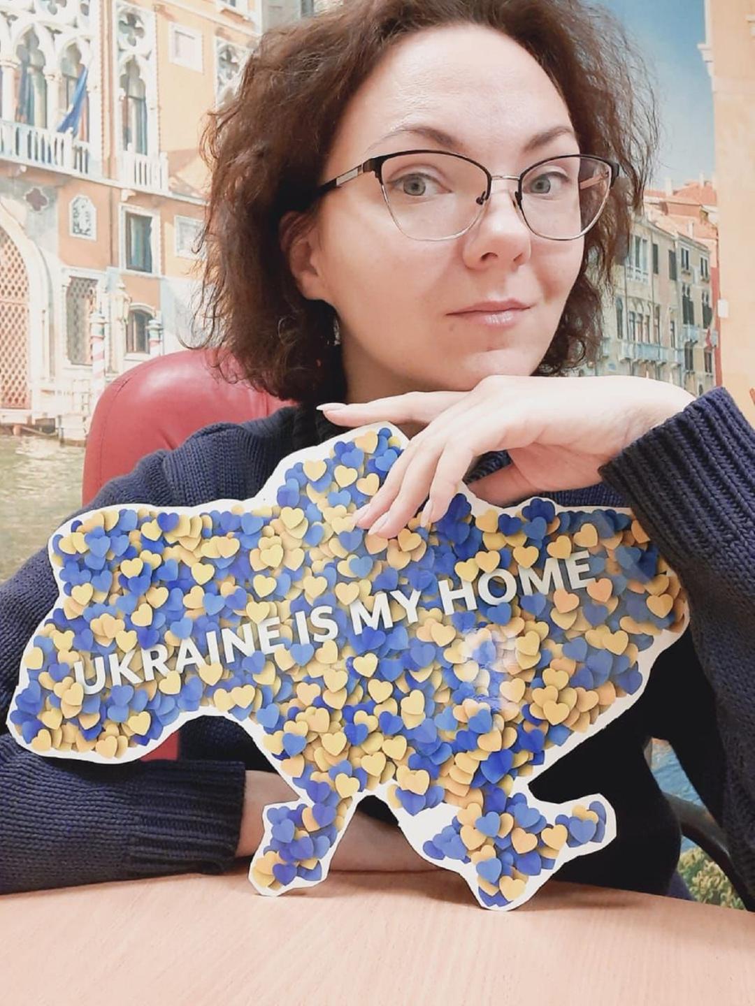 Eine Frau mit roten Haaren hält ein Schild mit der Aufschrift "Ukraine is my home".