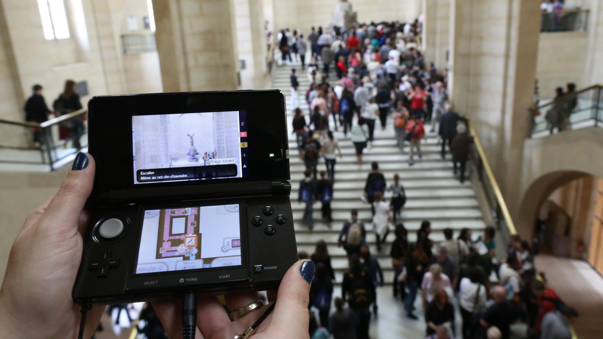 Eine Besucherin mit einem Nintendo 3DS als Führer in der Hand im Louvre. Eine Besucherin mit einem Nintendo 3DS als Führer in der Hand im Louvre.