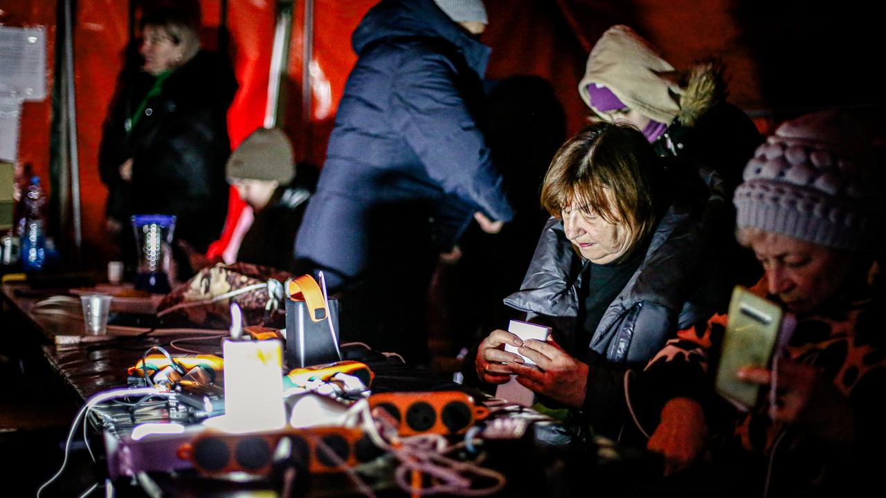 Menschen sitzen in einem Zelt, wärmen sich auf und laden ihre Handys auf. Menschen sitzen in einem Zelt, wärmen sich auf und laden ihre Handys auf.