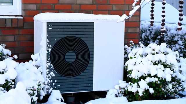 Wärme-Pumpe vor einem Wohn-Haus im Winter