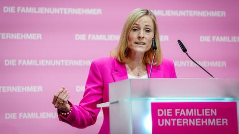 Marie-Christine Osterman steht an einem Redepult. Im Hintergrund zu sehen ist eine rosafarbene Wand mit der Aufschrift "Die Familienunternehmer".