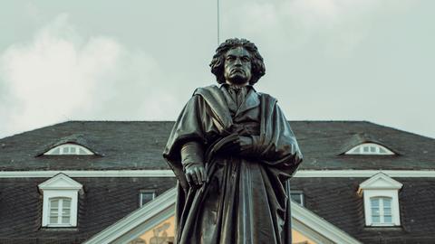 Blick auf die große Beethoven-Standfigur in Bonn, die den Komponisten mit wildem Haar und Falten werfenden Mantel zeigt.