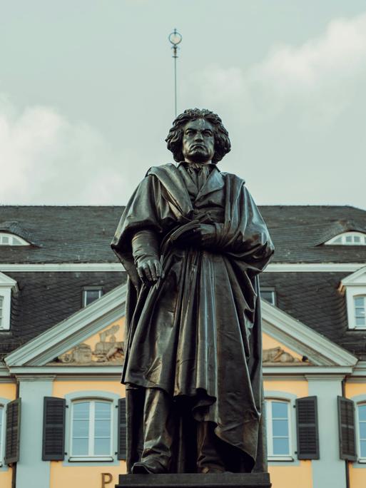 Blick auf die große Beethoven-Standfigur in Bonn, die den Komponisten mit wildem Haar und Falten werfenden Mantel zeigt.