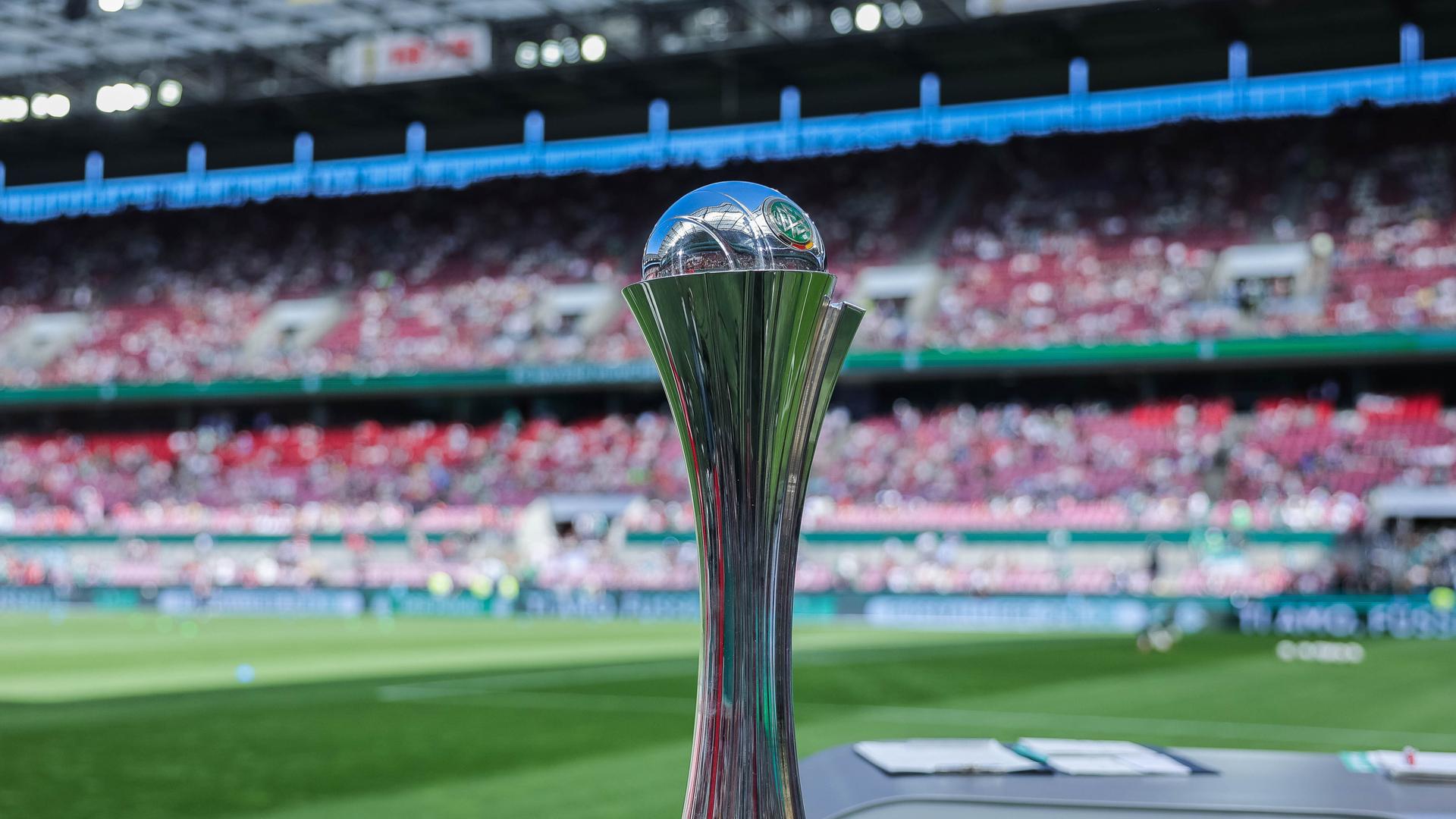 Das Bild zeigt den silbernen DFB Pokal der Frauen. Im Hintergrund ist ein Stadion zu erkennen.