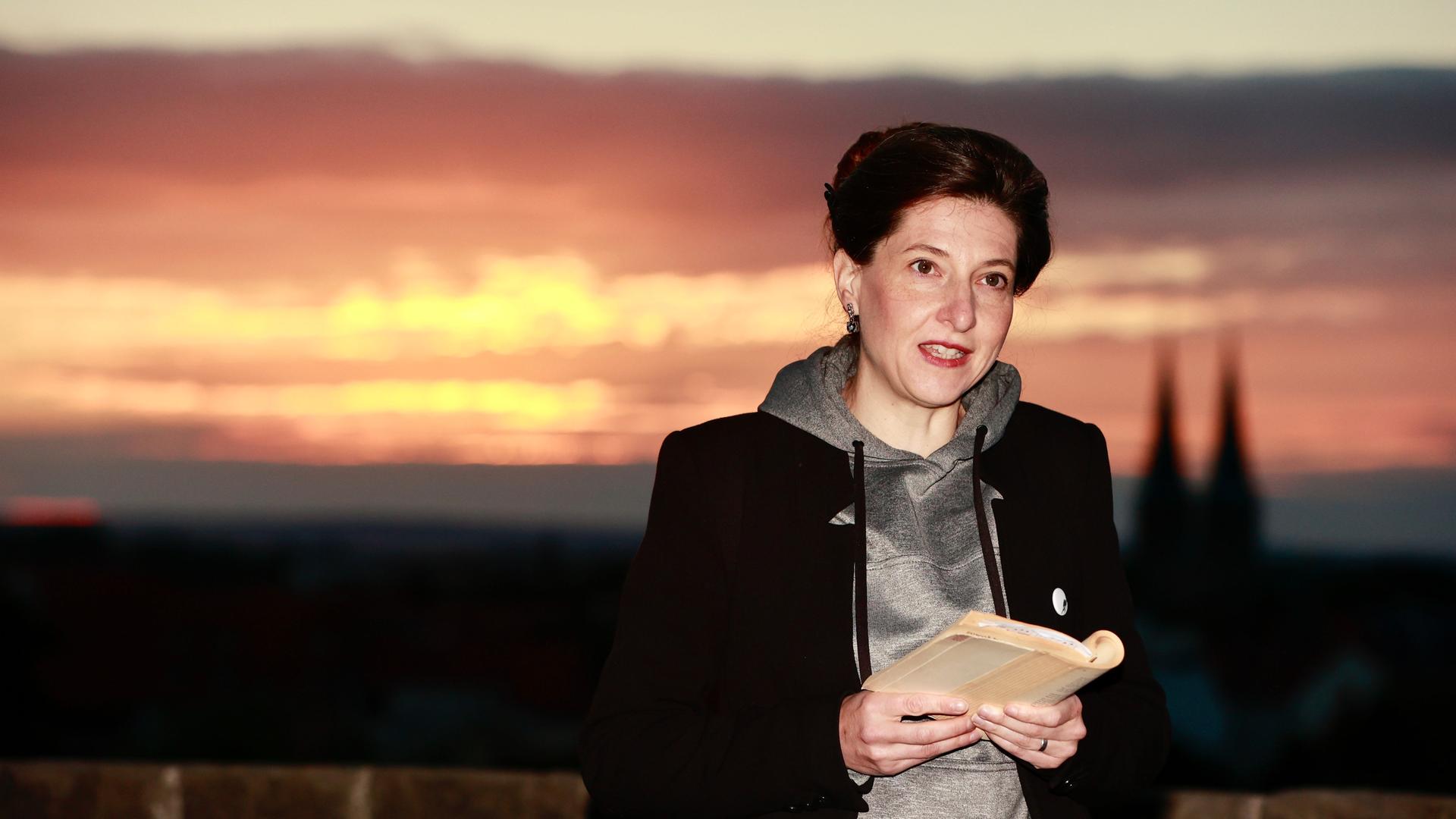 Schriftstellerin Daniela Danz steht bei Sonnenaufgang im Stiftsgarten der Stadt Quedlinburg und liest aus den Werken von Friedrich Gottlieb Kloppstock. 