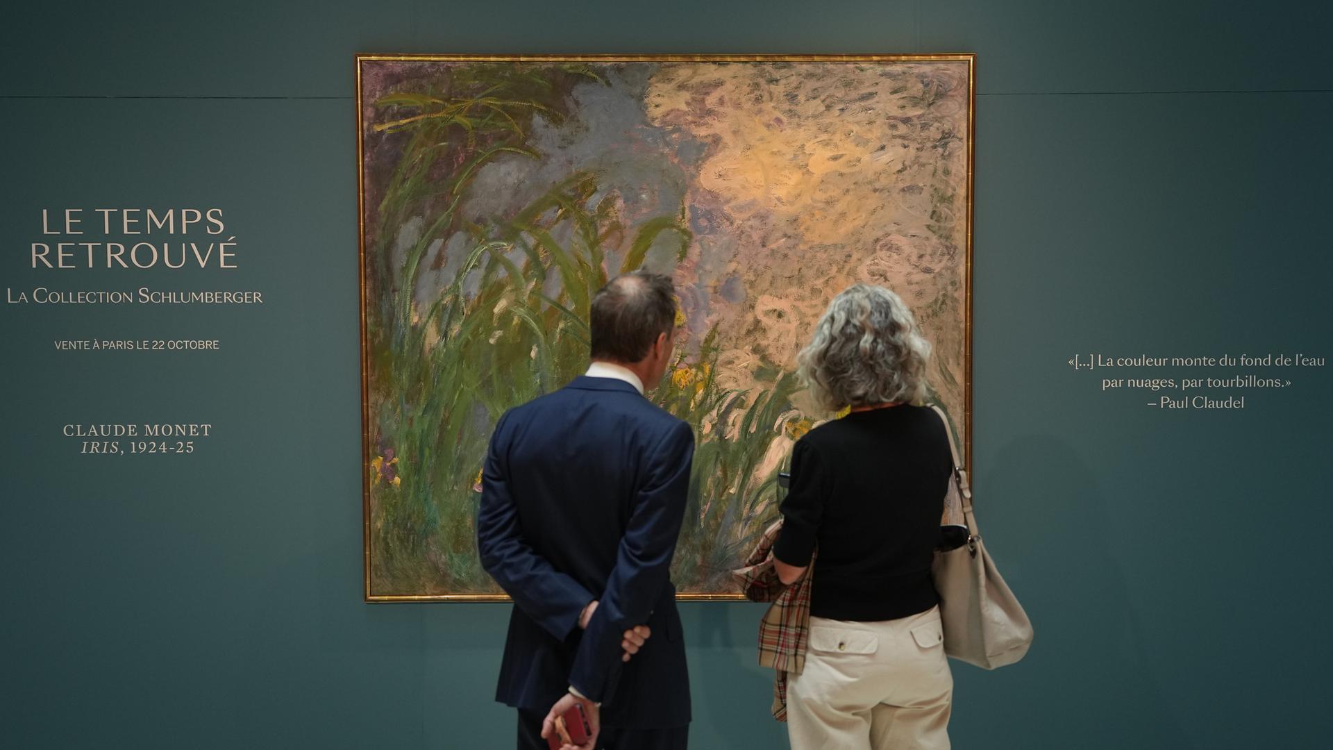 Zwei Personen stehen vor dem Gemälde „Iris“ von Claude Monet im Auktionshaus Sotheby’s in Paris.