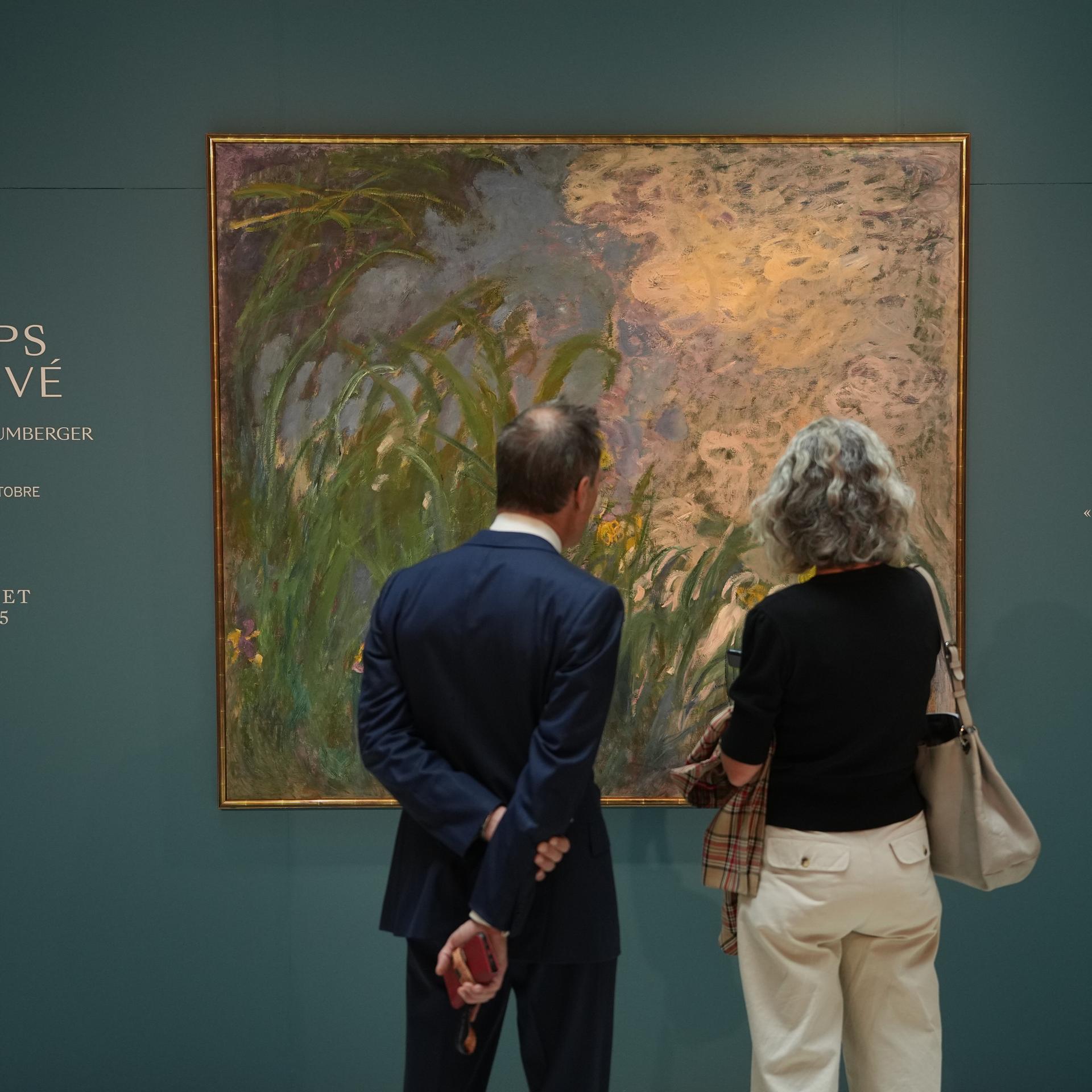 Zwei Personen stehen vor dem Gemälde „Iris“ von Claude Monet im Auktionshaus Sotheby’s in Paris.